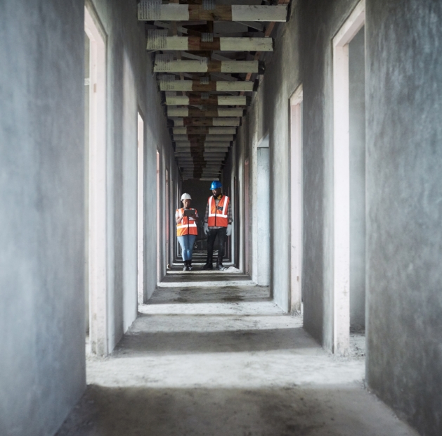Two workers from JP Gravel Construction walk through an empty hallway, showcasing a quiet work environment.